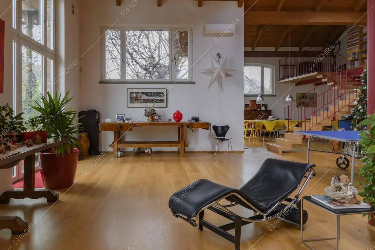 Chaise longue nella luminosa sala dalle grandi vetrate e con pavimento in parquet