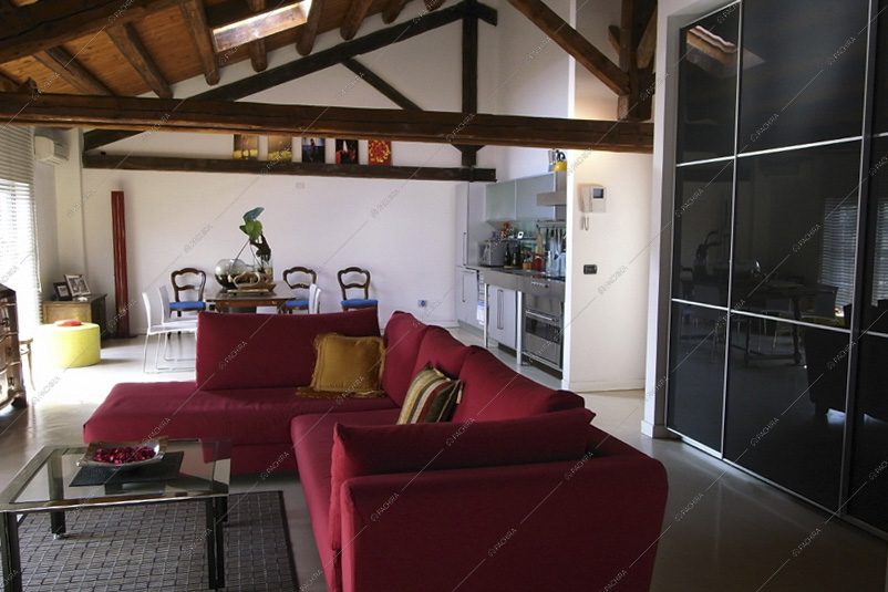 Divano rosso angolare, soffitto con travi a vista e lucernario