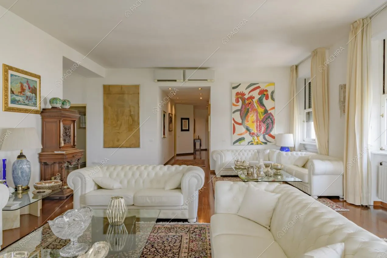 Dai divani in pelle del soggiorno, dalle pareti bianche, vista sul corridoio con pavimento in parquet