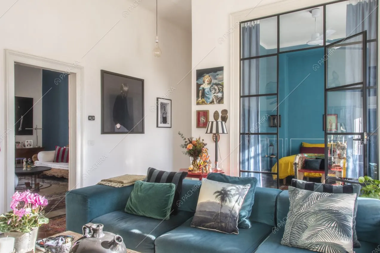 Divano in velluto blu con cuscini e quadro moderno