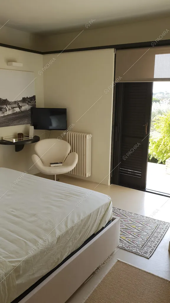 Sedia di design in pelle bianca e televisione nella camera da letto