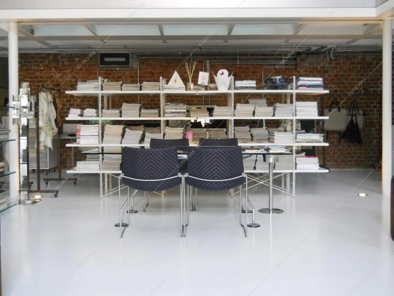 Tavolo con piano di appoggio in vetro e libreria che separa lo studio dall'open space