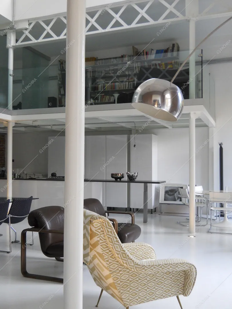 Dalla zona living vista sulla cucina con isola e sulla biblioteca sul soppalco