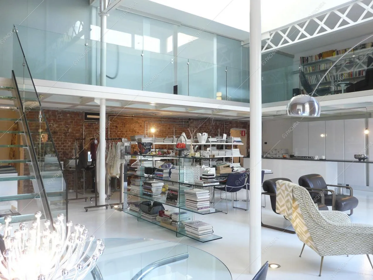 Dalle scale in vetro vista sul soppalco, sulla libreria che separa lo studio e sulla cucina