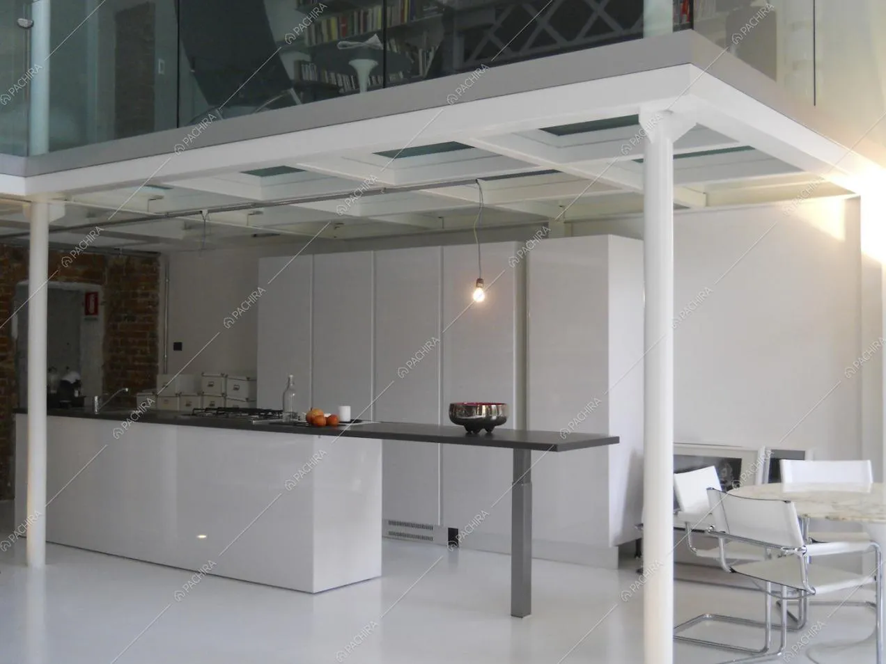 Cucina a vista bianca e soppalco con libreria