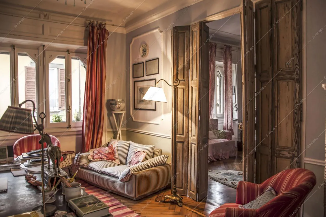 Studio con porta in legno delabrè, divano e poltrona