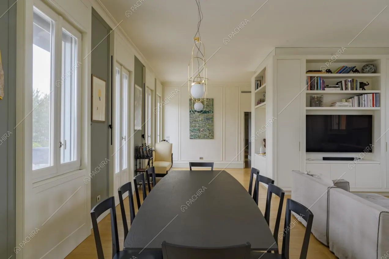 Sala con tavolo da pranzo da dieci posti, pavimento in parquet e porte-finestre