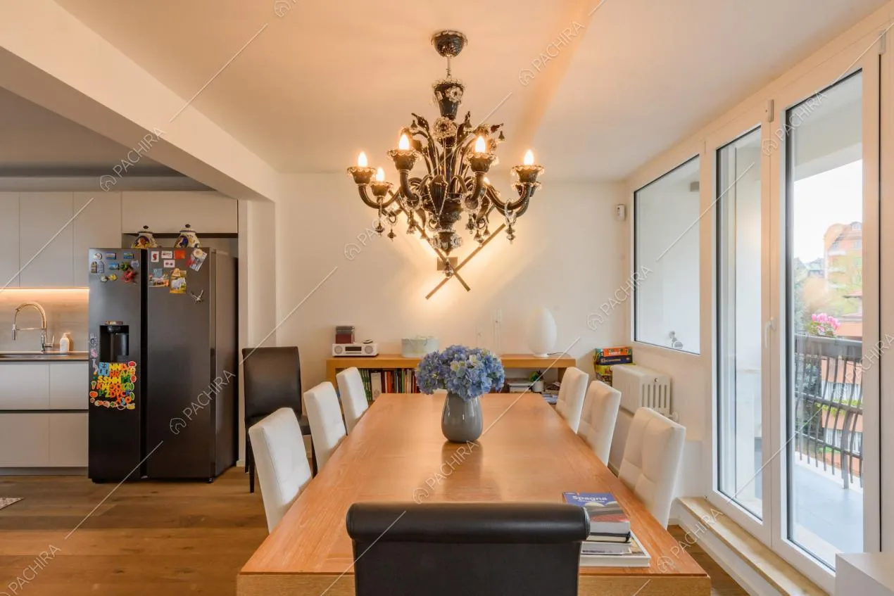 Tavolo da pranzo in legno e sedie bianche nella zona living con cucina a vista