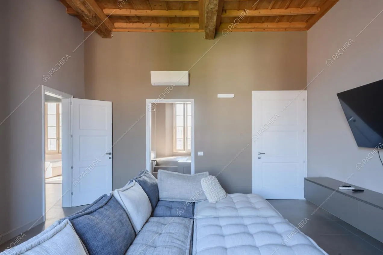 Soffitto a cassettoni nel luminoso salotto con pareti e pavimento grigi
