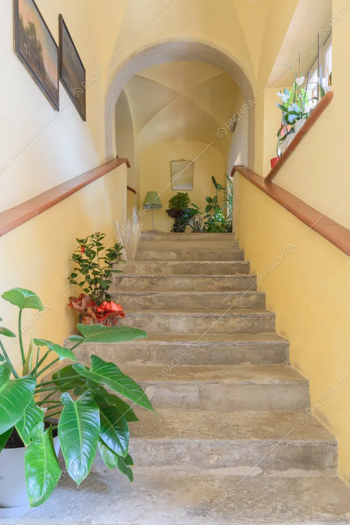 Scale con pareti gialle, soffitto in volte a crociera e corrimano in mattonelle rosse