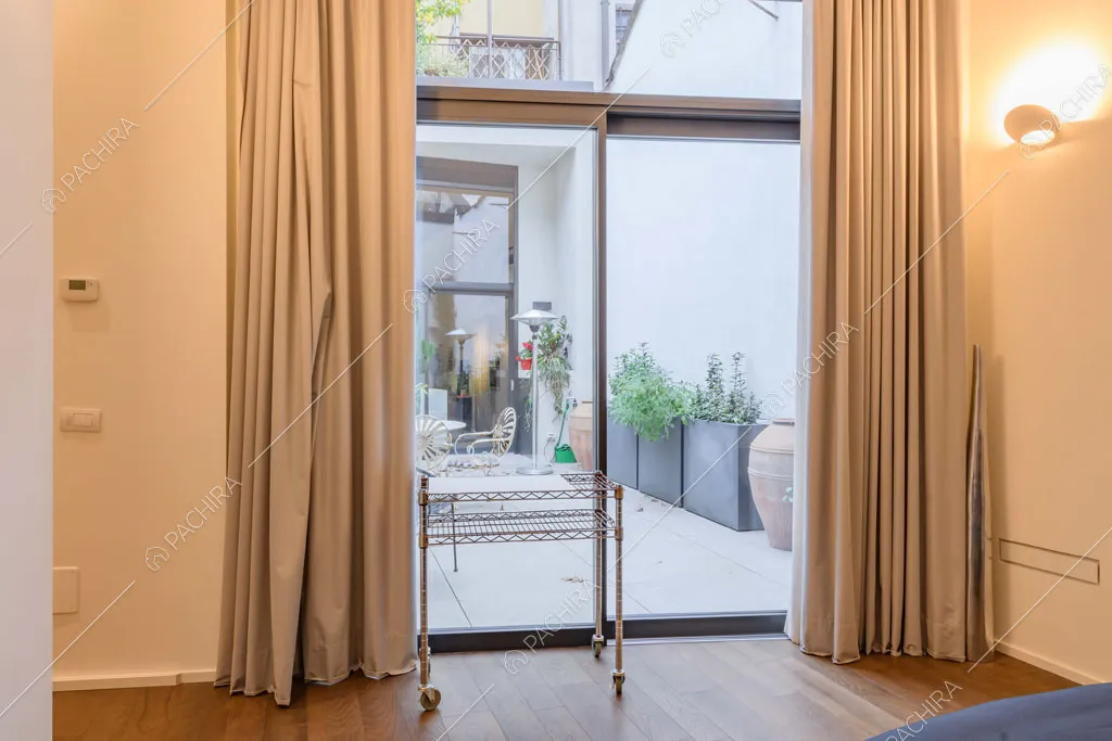 Luminosa camera da letto con pareti bianche, pavimento in parquet e vetrate
