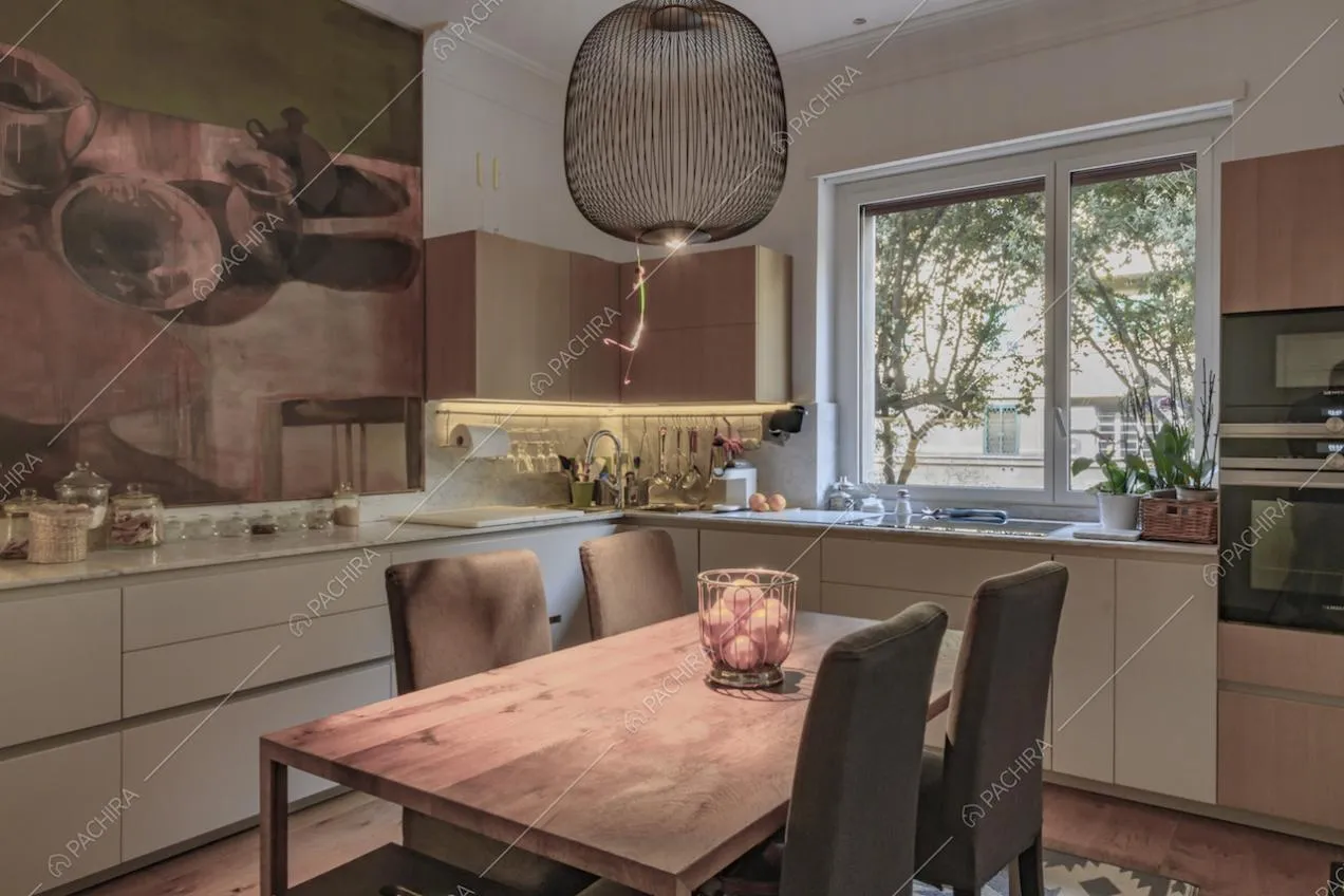 Nella cucina con vetrata e fornelli a induzione, tavolo da pranzo in legno e lampadario di design