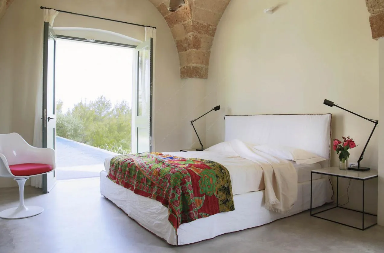 Letto matrimoniale nella luminosa camera con porta-finestra e mattoni a vista