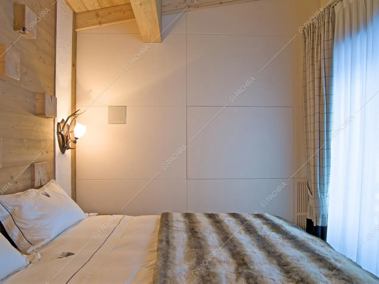 Luminosa camera da letto matrimoniale con soffitto in travi in legno a vista