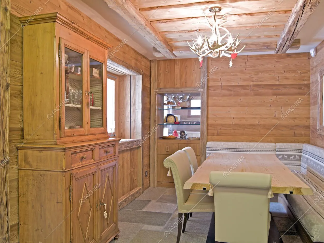 Sala da pranzo dalle pareti in legna, con soffitto in travi in legno a vista e pavimento in lastre di pietra