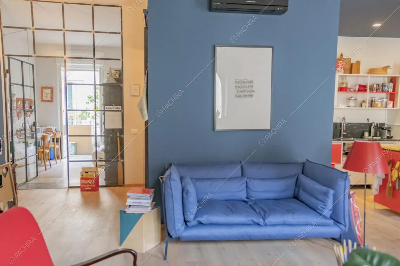 Divano blu su pavimento in parquet e quadro appeso alla parete