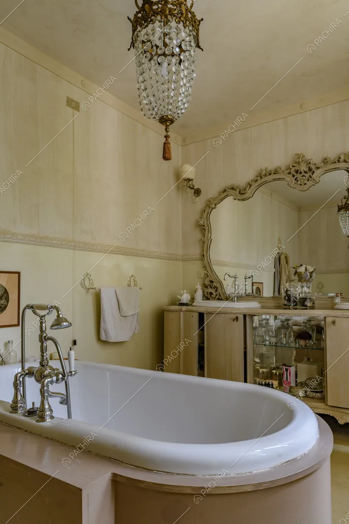 Bagno con vasca, specchio con cornice dorata e lavorata e carta da parati