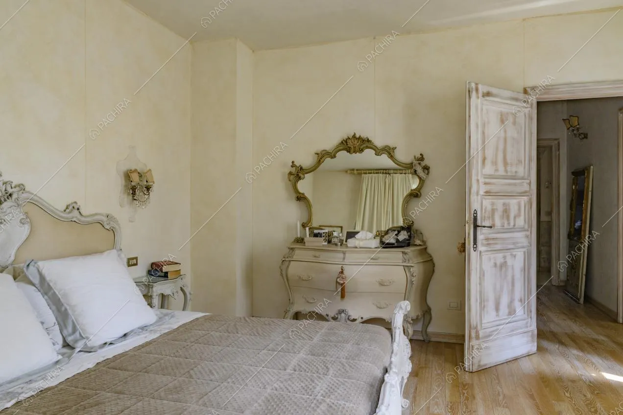 Camera da letto matrimoniale dalle pareti color crema e dal pavimento in parquet