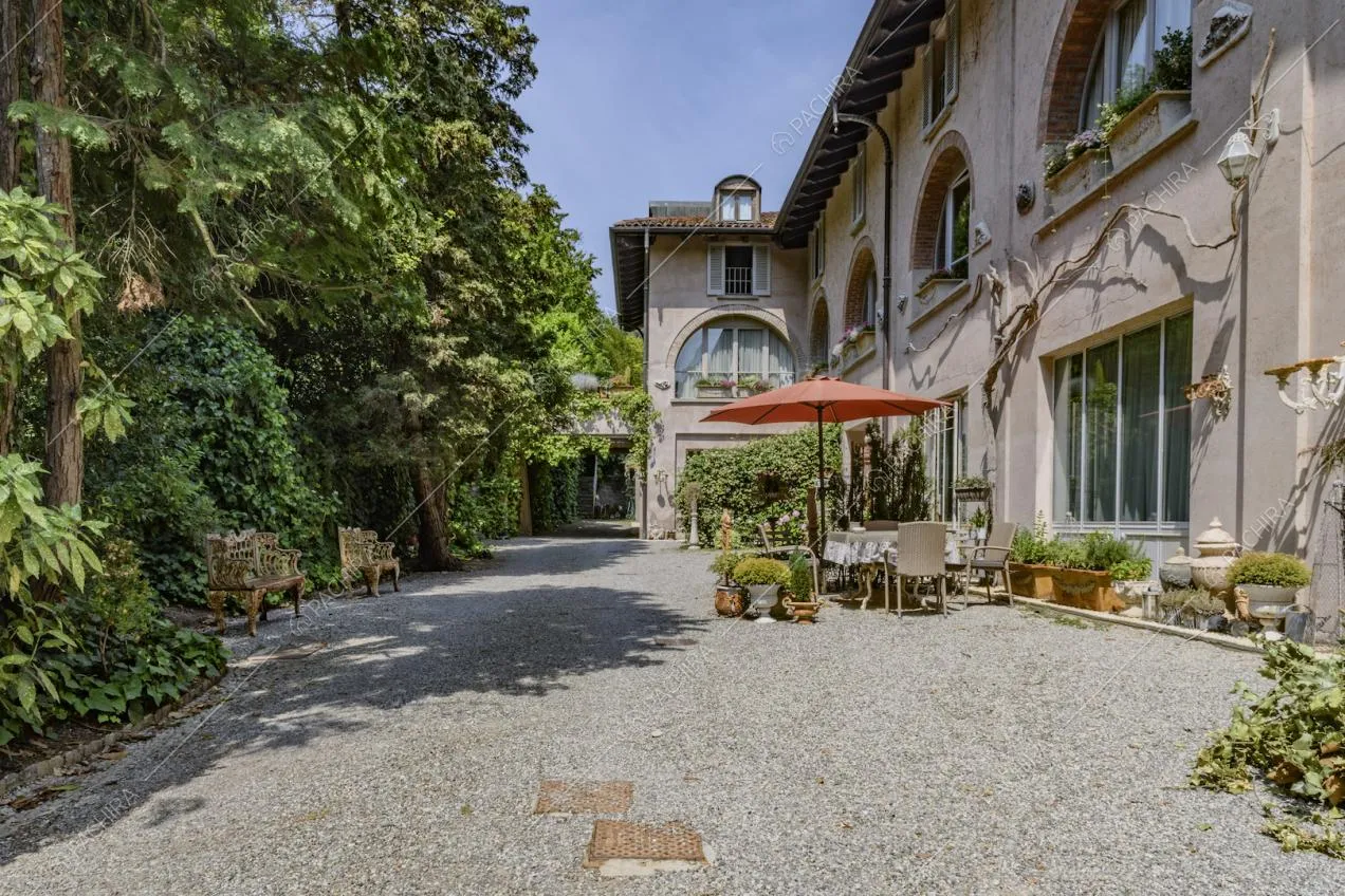 Tavolo da pranzo con ombrellone rosso e piante negli esterni della location