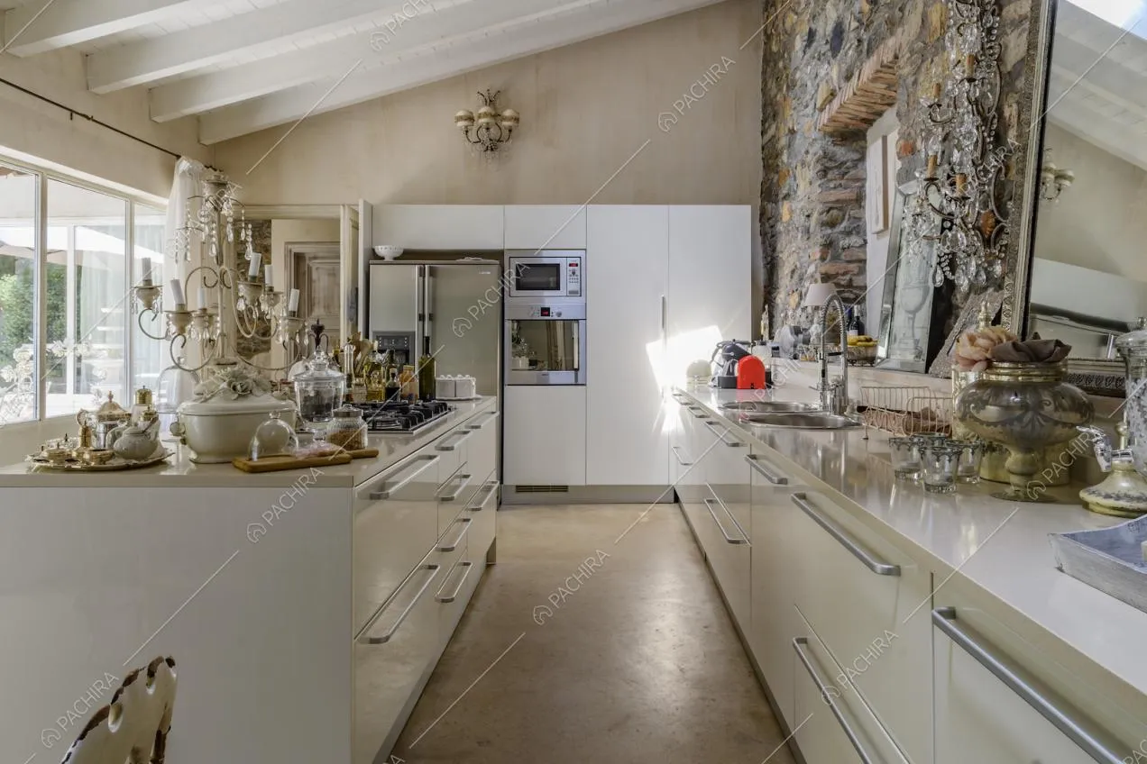 Cucina a isola con fornelli a gas, parete in pietra a vista e grandi vetrate