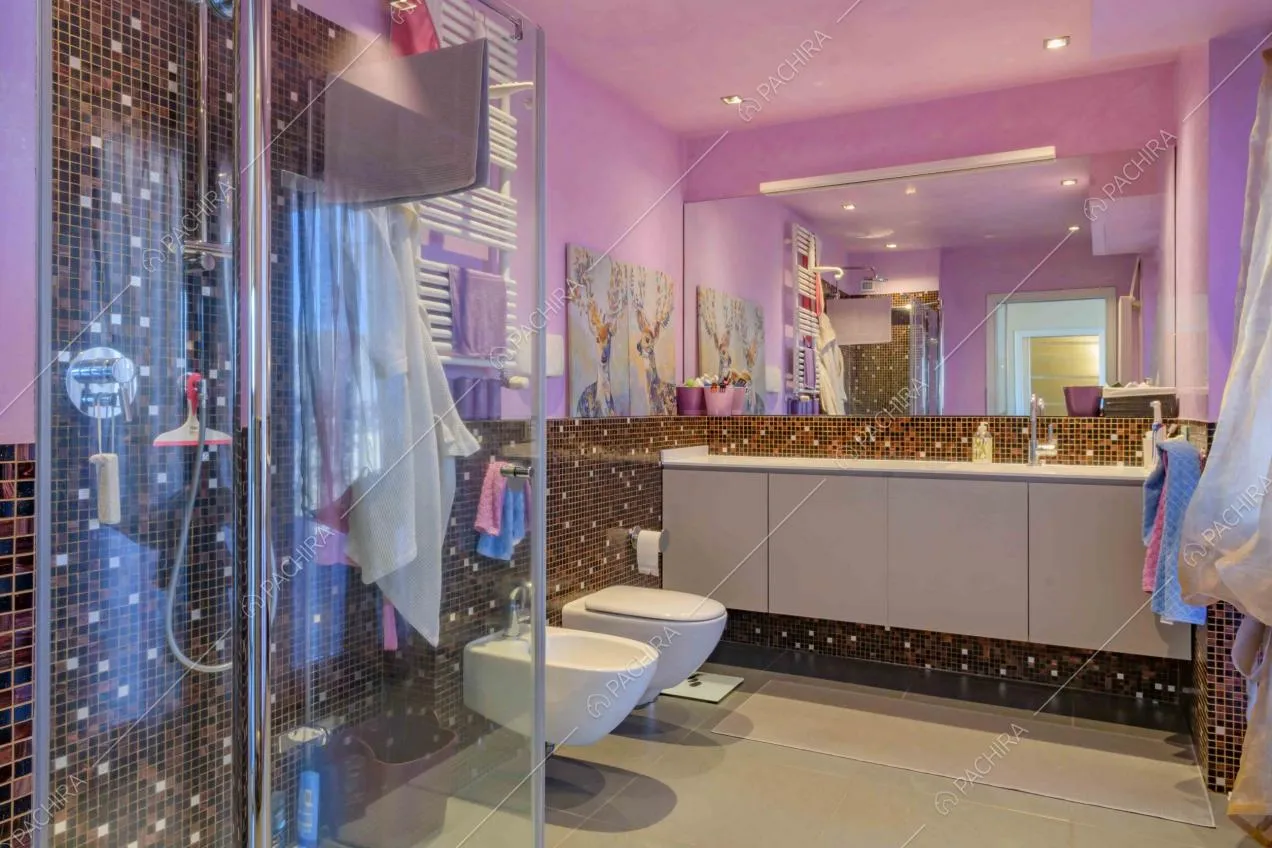 Bagno privato dalle pareti viola e con piastrelline con box doccia