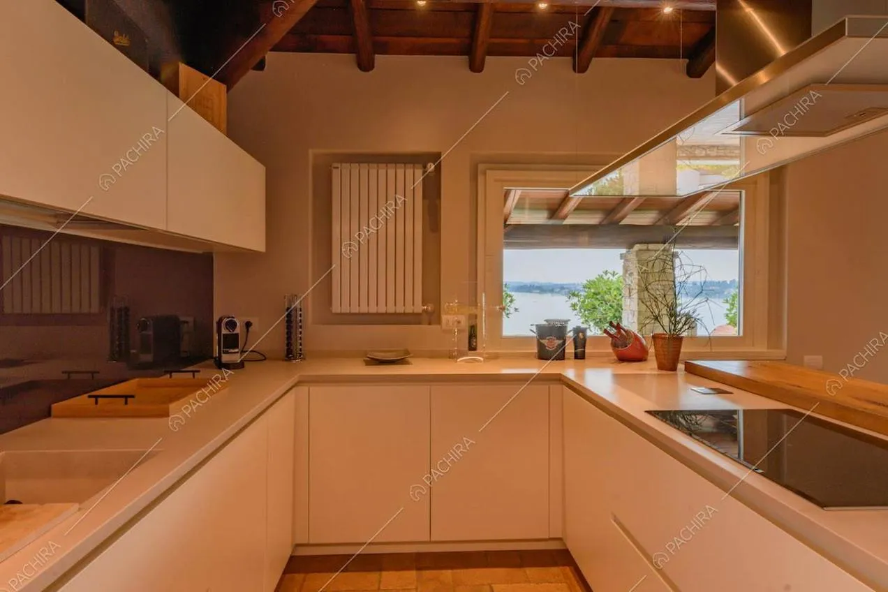 Cucina bianca a parete con fornelli a induzione e soffitto in travi in legno a vista