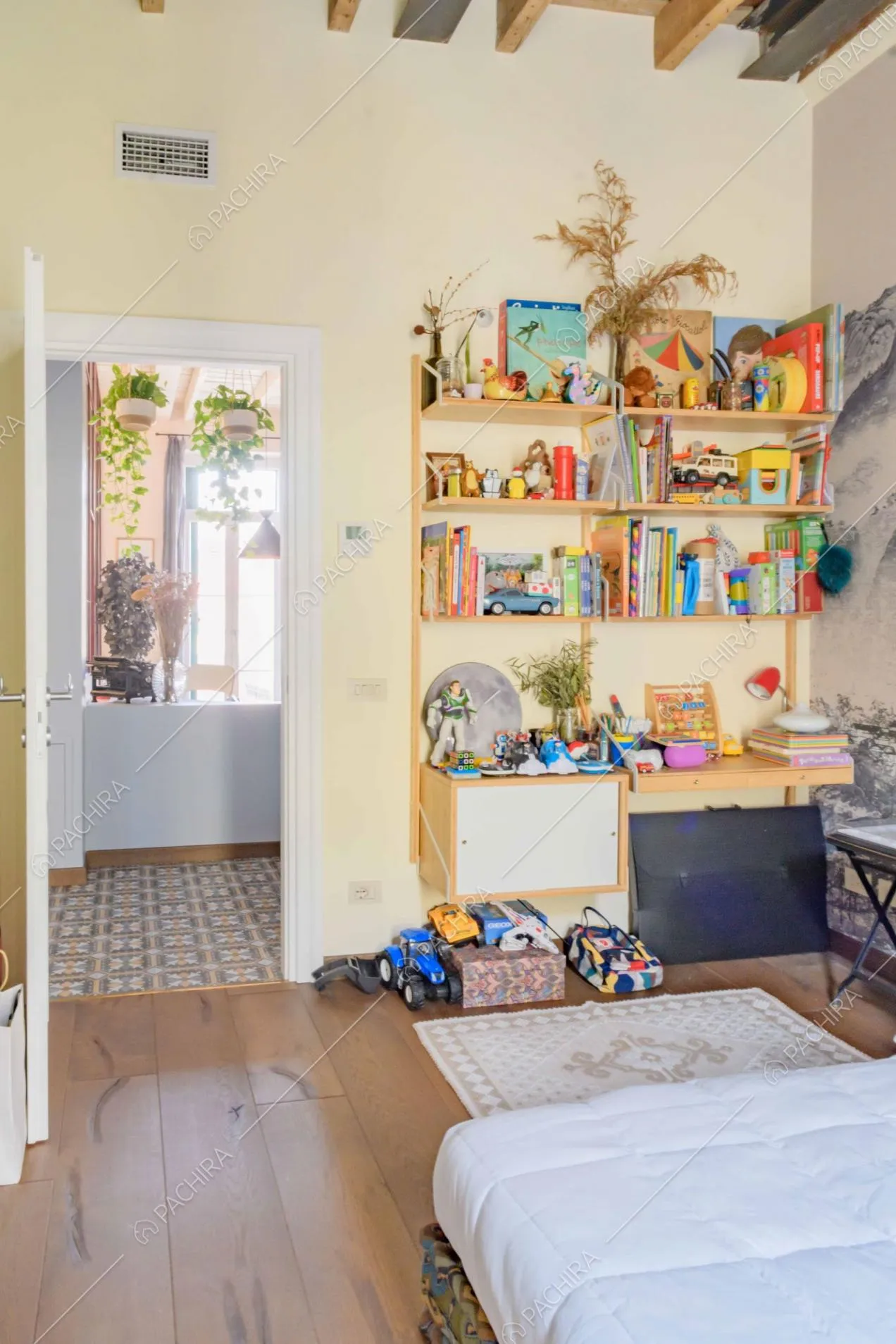 Camera da bambini con pavimento in parquet, pareti gialle e libreria