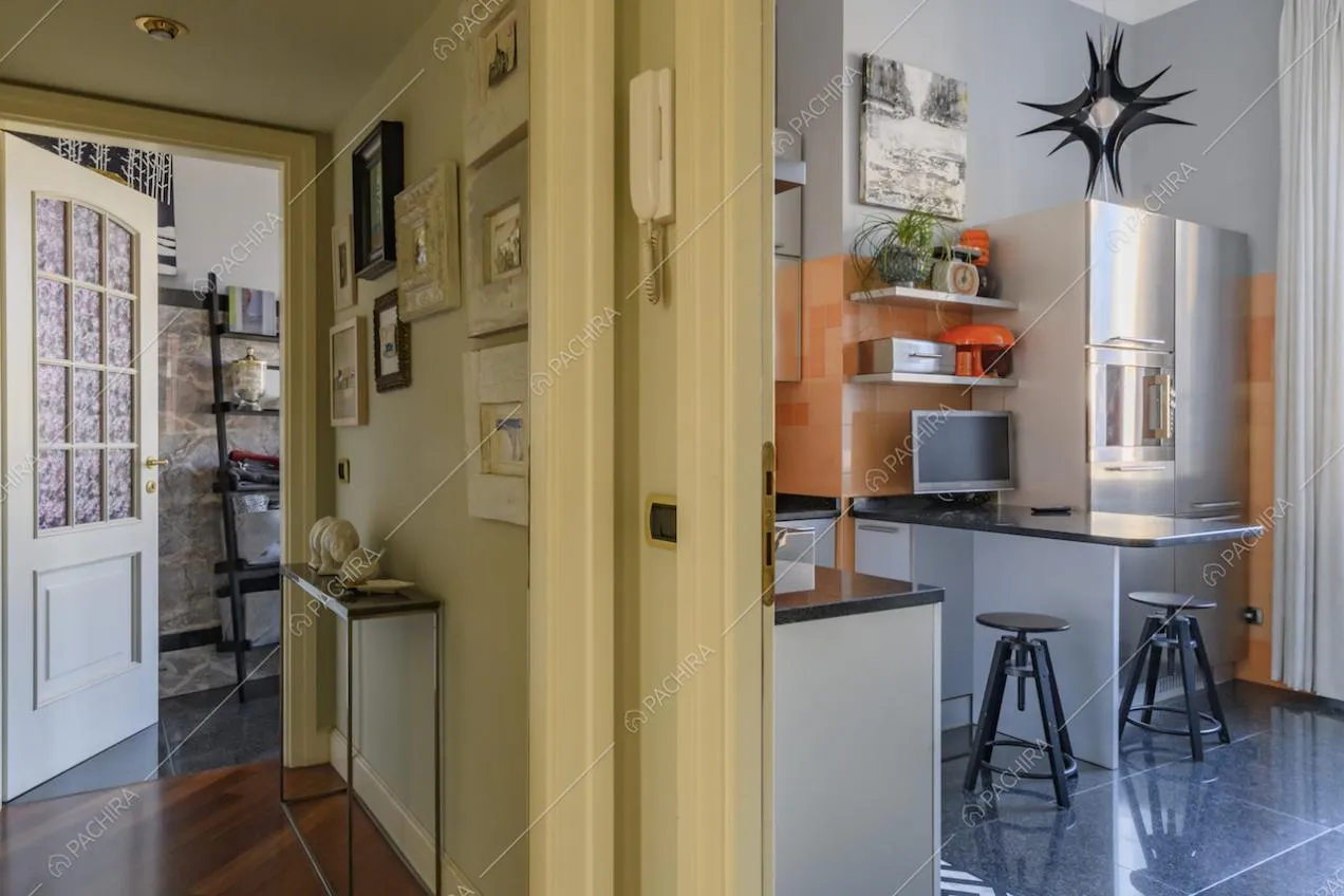 Corridoio con quadretti appesi alla parete e vista sulla cucina