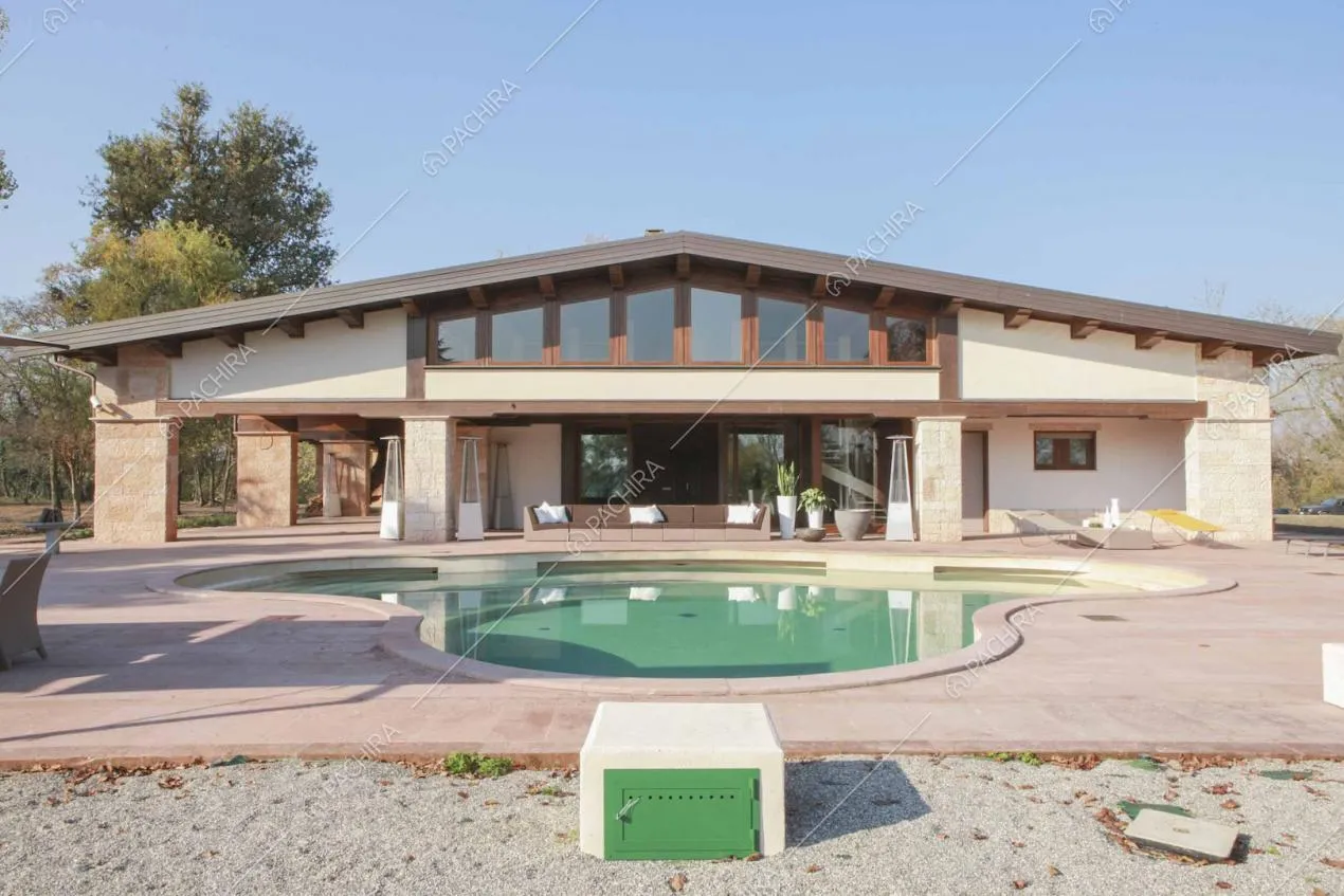 Piscina davanti alla villa dagli esterni bianchi e con vetrate