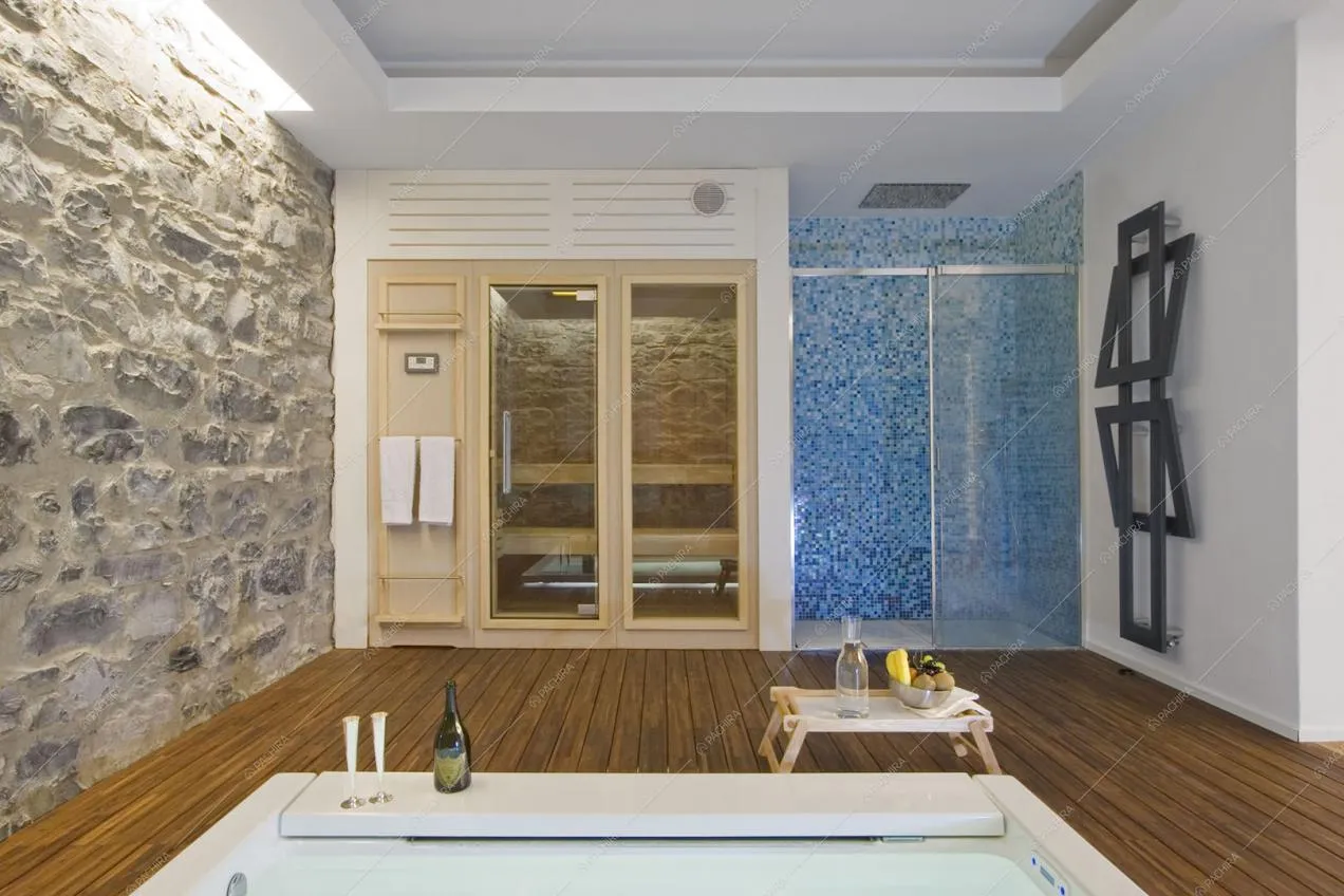 Box doccia con piastrelline blu, scorcio sulla sauna dalla piscina