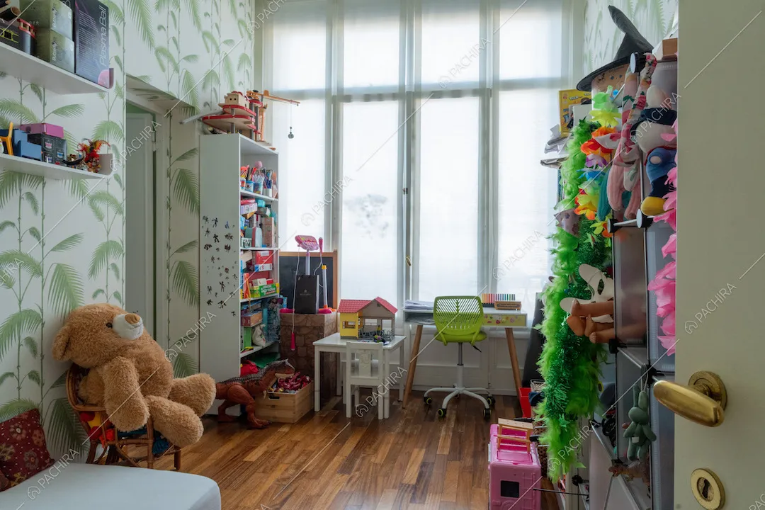 Camera da letto da bambini con carta da parati illuminata dalle ampie vetrate