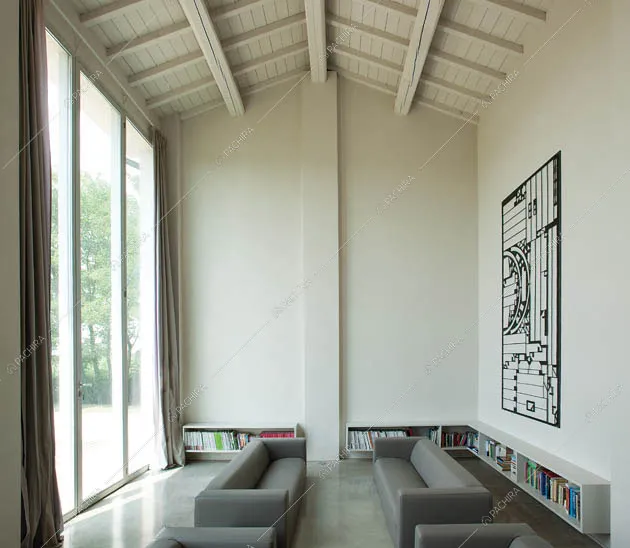 Zona living con divani grigi e soffitto alto