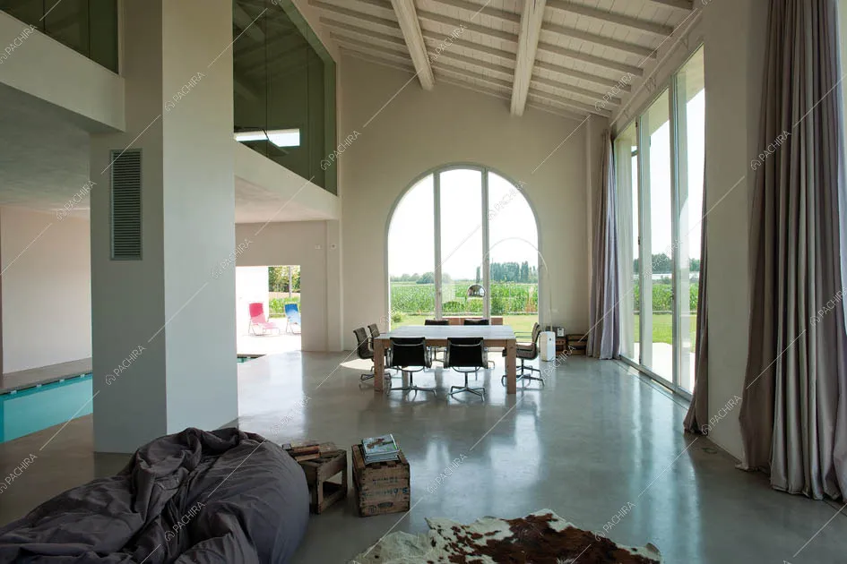 Zona living con tavolo in legno, vetrate e piscina