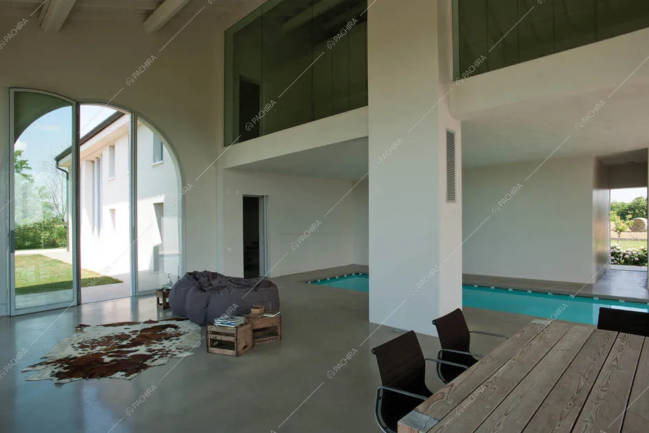 Tavolo in legno, pouf, piscina e scorcio sul soppalco