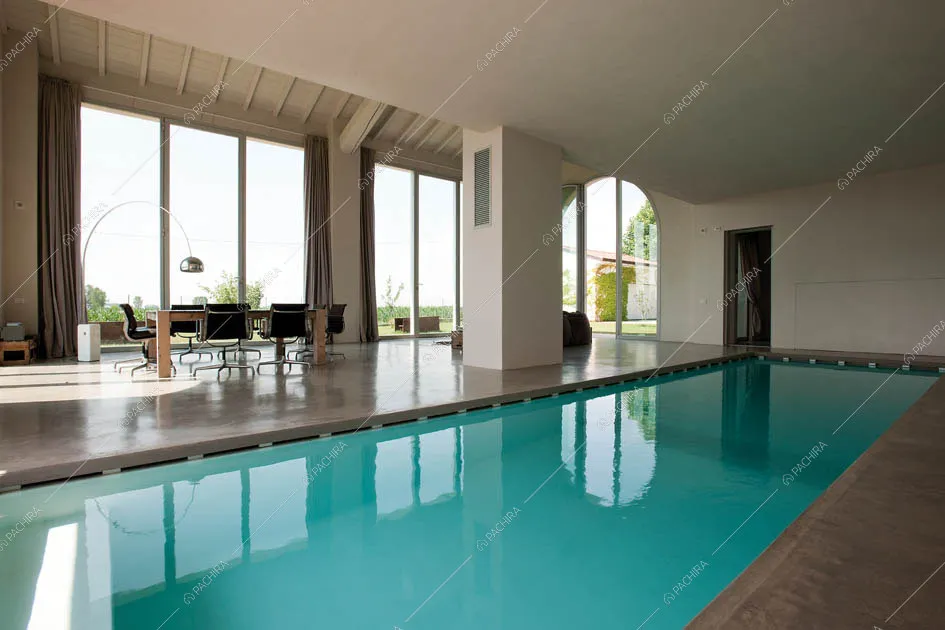 Piscina coperta, pavimento in cemento lisciato, tavolo e vetrate