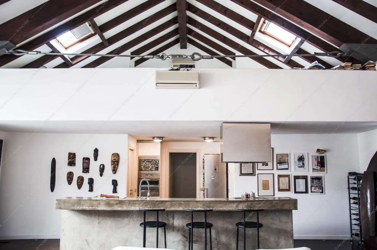 Vista della cucina, sgabelli neri, soffitto con travi a vista