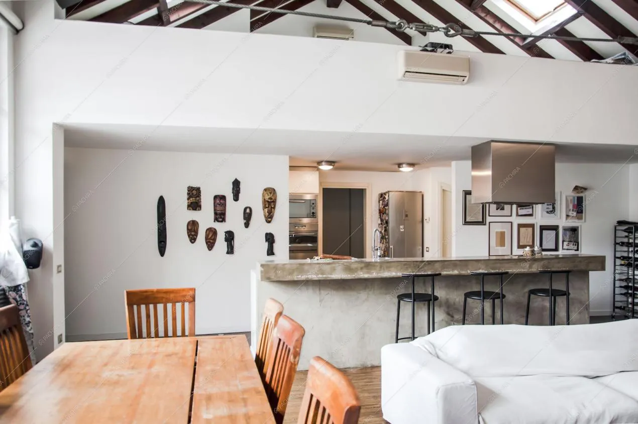 Open space con tavolo da pranzo, divano bianco e cucina