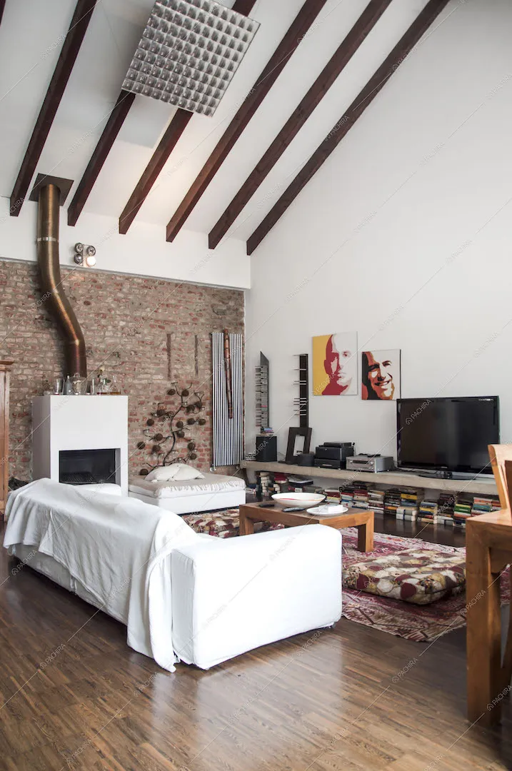 Zona living con divano, tappeti e soffitto con travi a vista