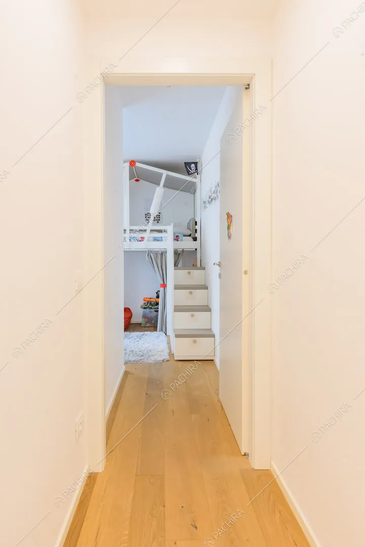 Dal luminoso corridoio con pavimento in parquet e pareti bianche vista sulla camera dei bambini
