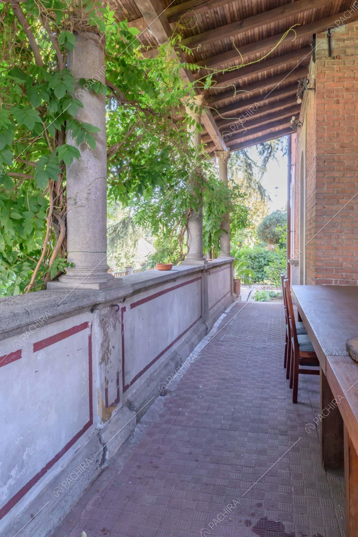 Corridoio della veranda con balconata affrescata, colonne bianche e mura in mattoni rossi a vista