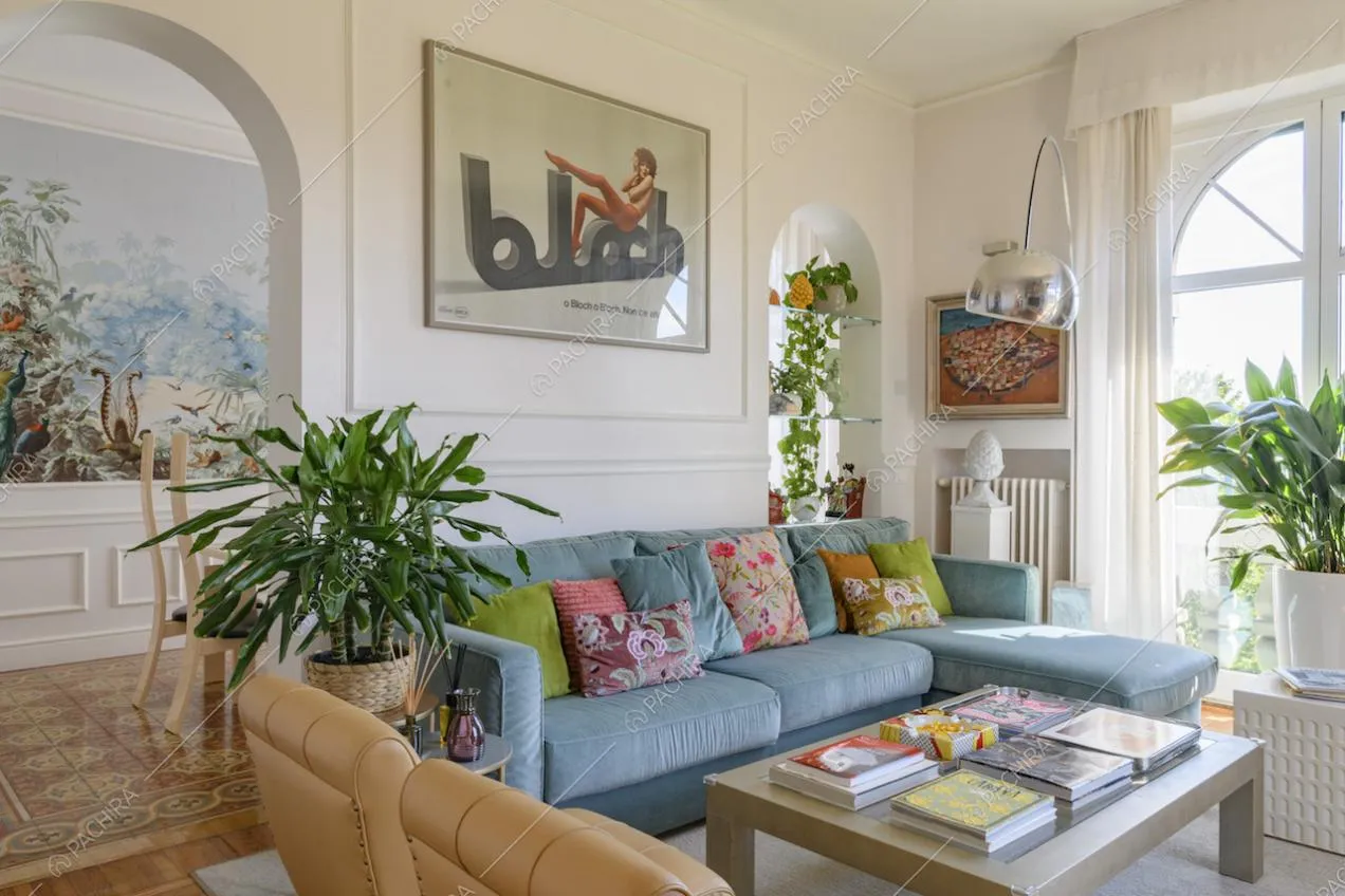 Salotto con boiserie alle pareti e accesso alla sala da pranzo tramite archi