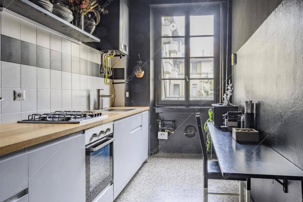 Cucina a parete con mobili chiari e finestra