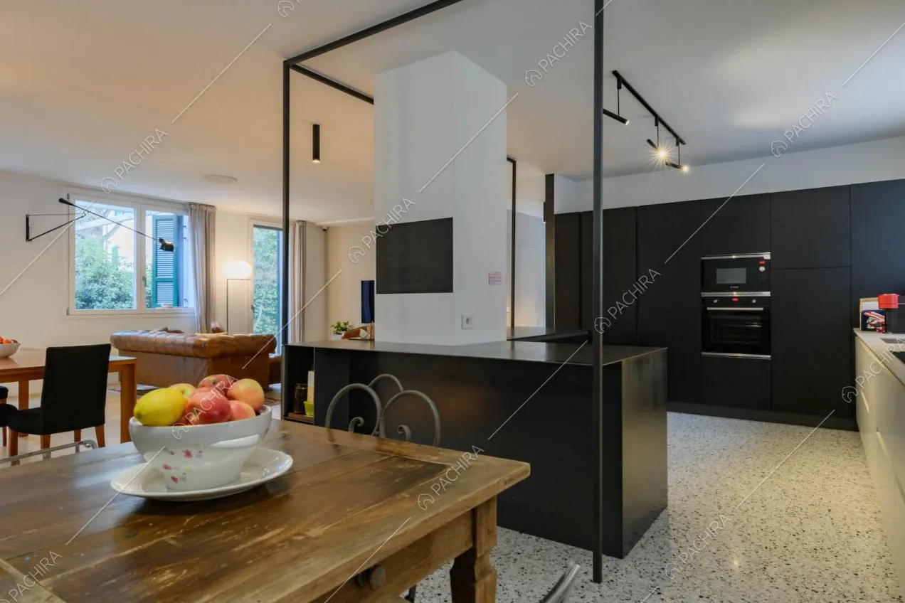 Cucina a parete a vista con pavimento in piastrelle, tavolo da pranzo in legno e pareti bianche 