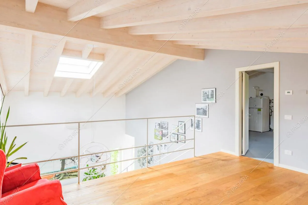 Soppalco con pavimento in parquet e soffitto in travi in legno a vista con lucernario