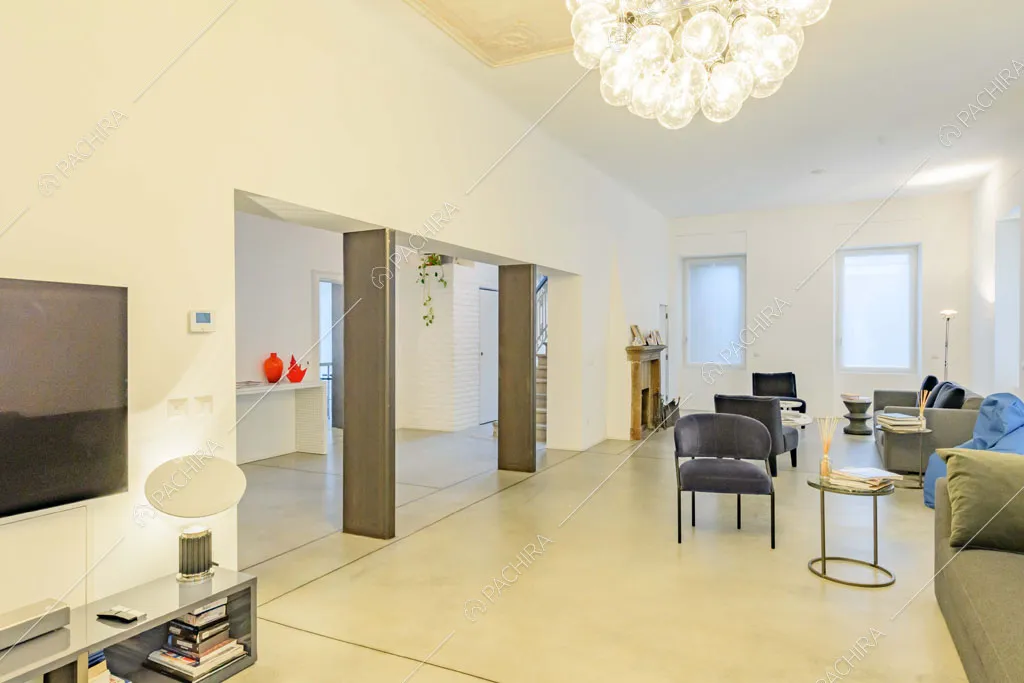 Lampadario di design nella grande zona living con boiserie sul soffitto e divani