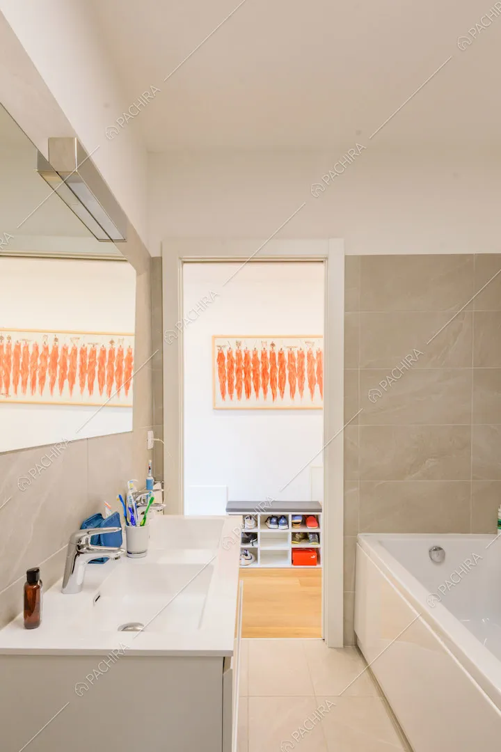 Pareti e pavimento grigi nel bagno con vasca e vista sul corridoio