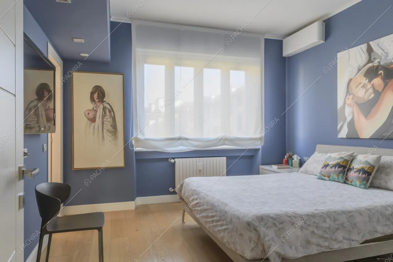 Camera da letto matrimoniale con pareti blu e ampia finestra