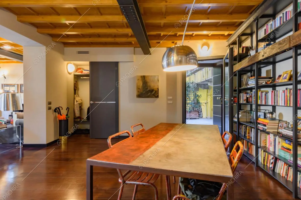 Dal tavolo da pranzo nella sala con travi in legno a vista sul soffitto scorcio sul cortile interno