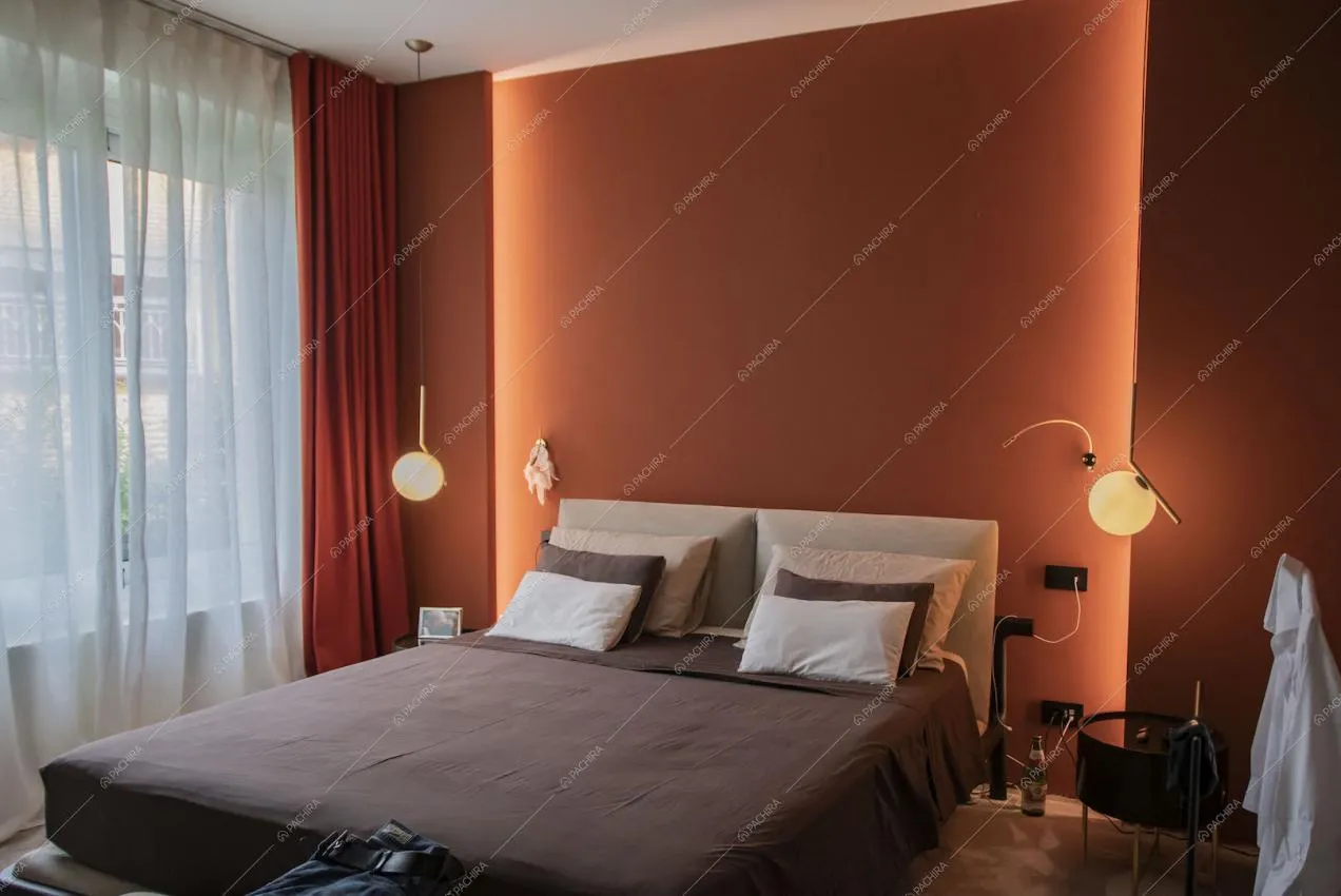 Camera da letto matrimoniale con parete arancione e vetrate