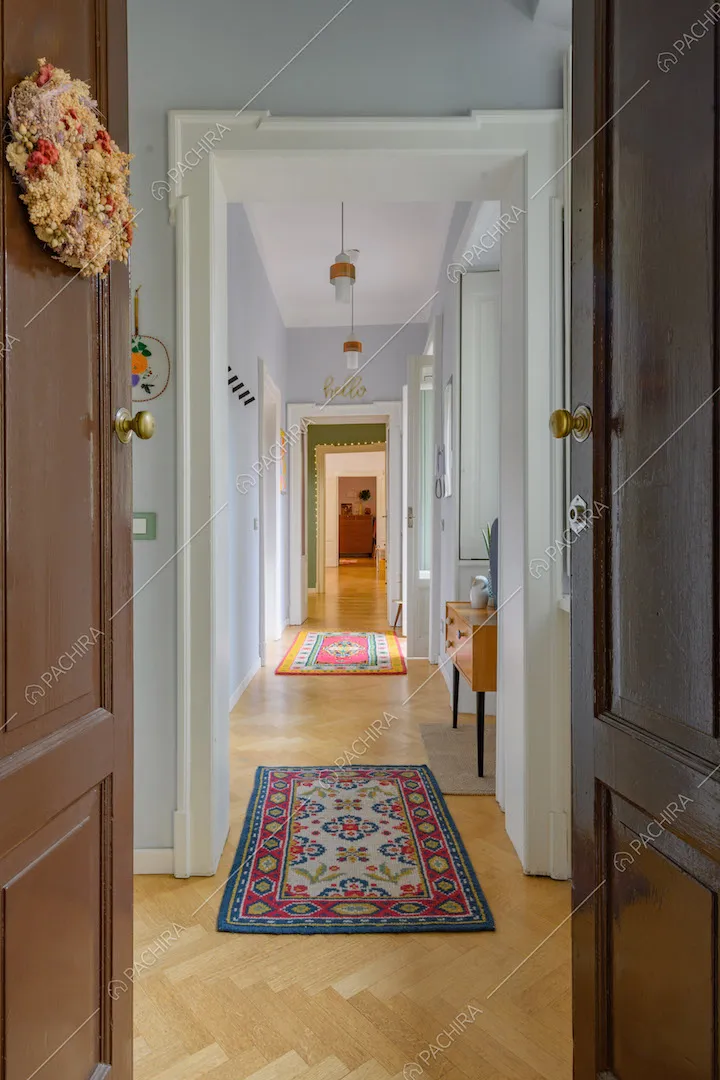 Dalla porta d'ingresso vista sul lungo corridoio con pavimento in parquet a spina di pesce